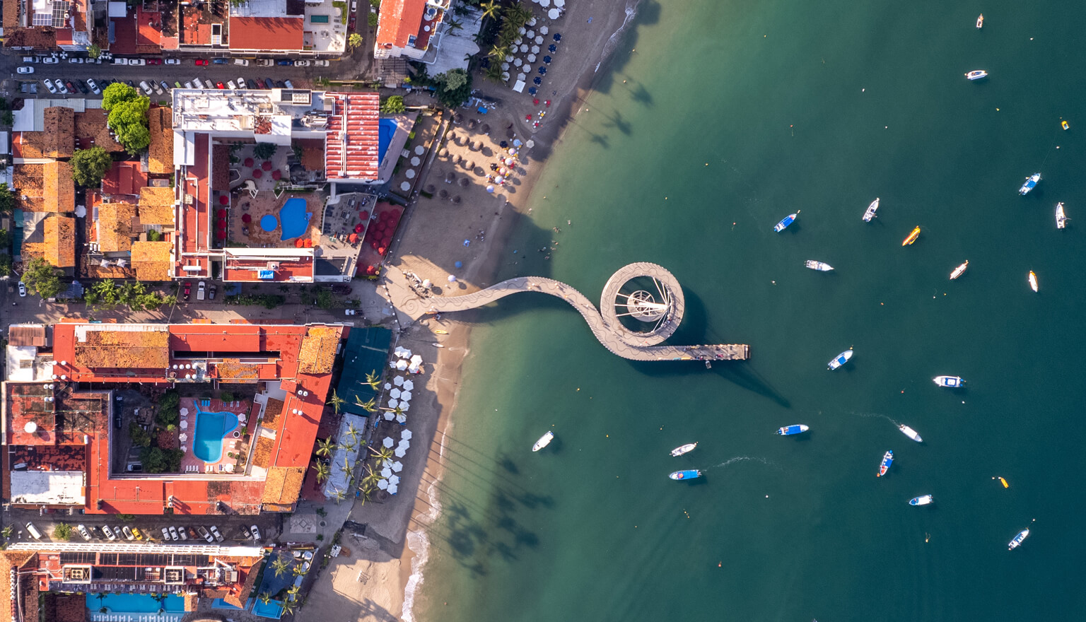 Birds eye view of a beachside with boats in the water.