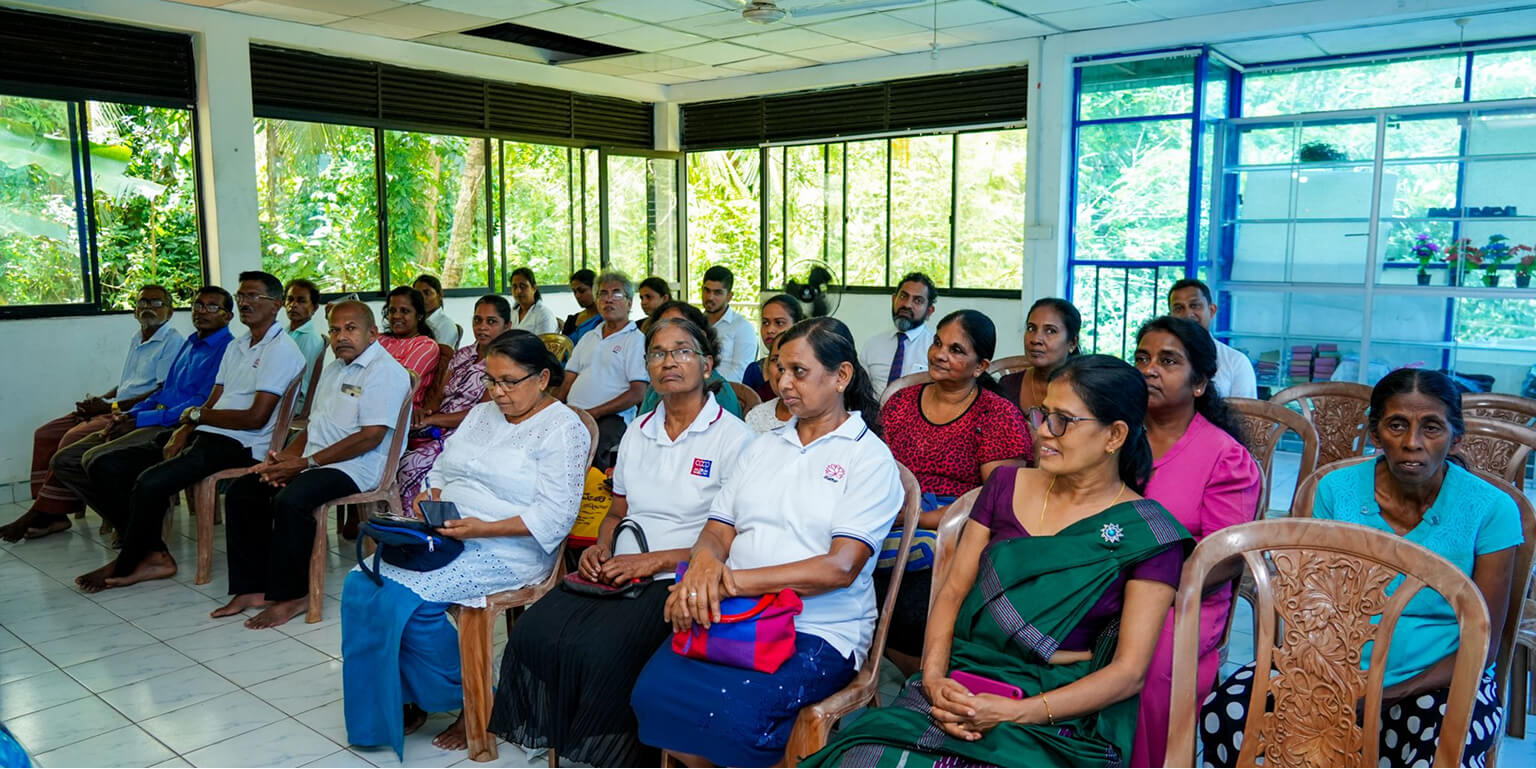 Women and men sitting in chairs attending training.