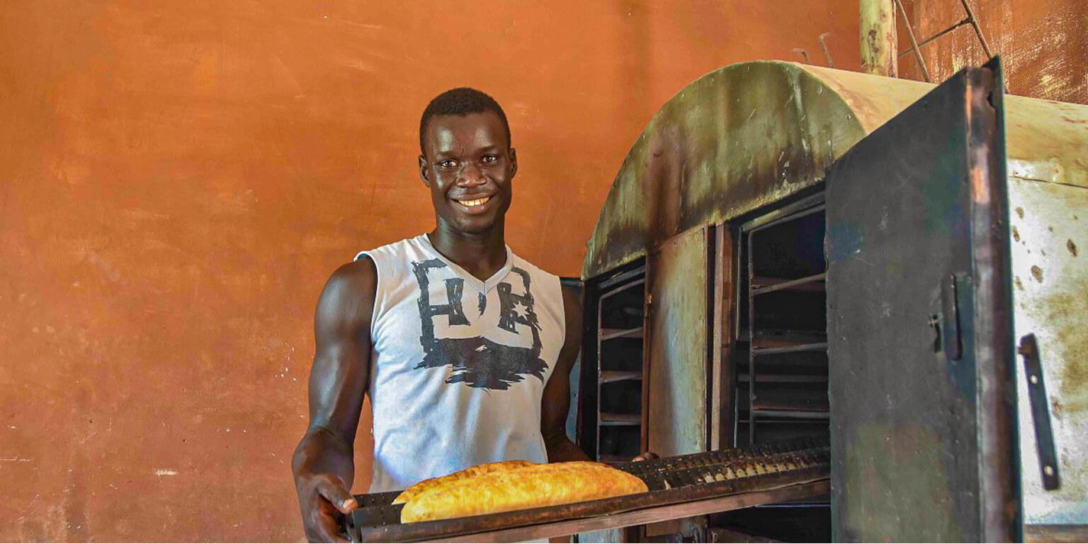 Man standing in front of an oven baking bread